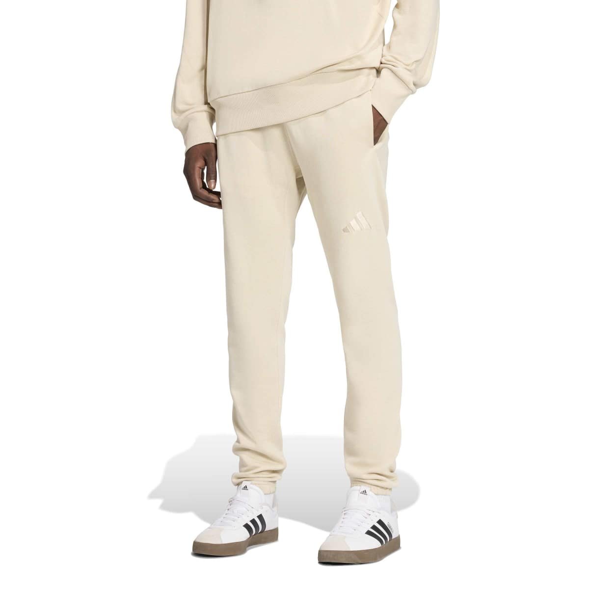 Šviesiai kreminės vyriškos Adidas ALL SZN sportinės kelnės su siaurėjančiomis klešnėmis ir mažu siuvinėtu logotipu, modelis KC3170.