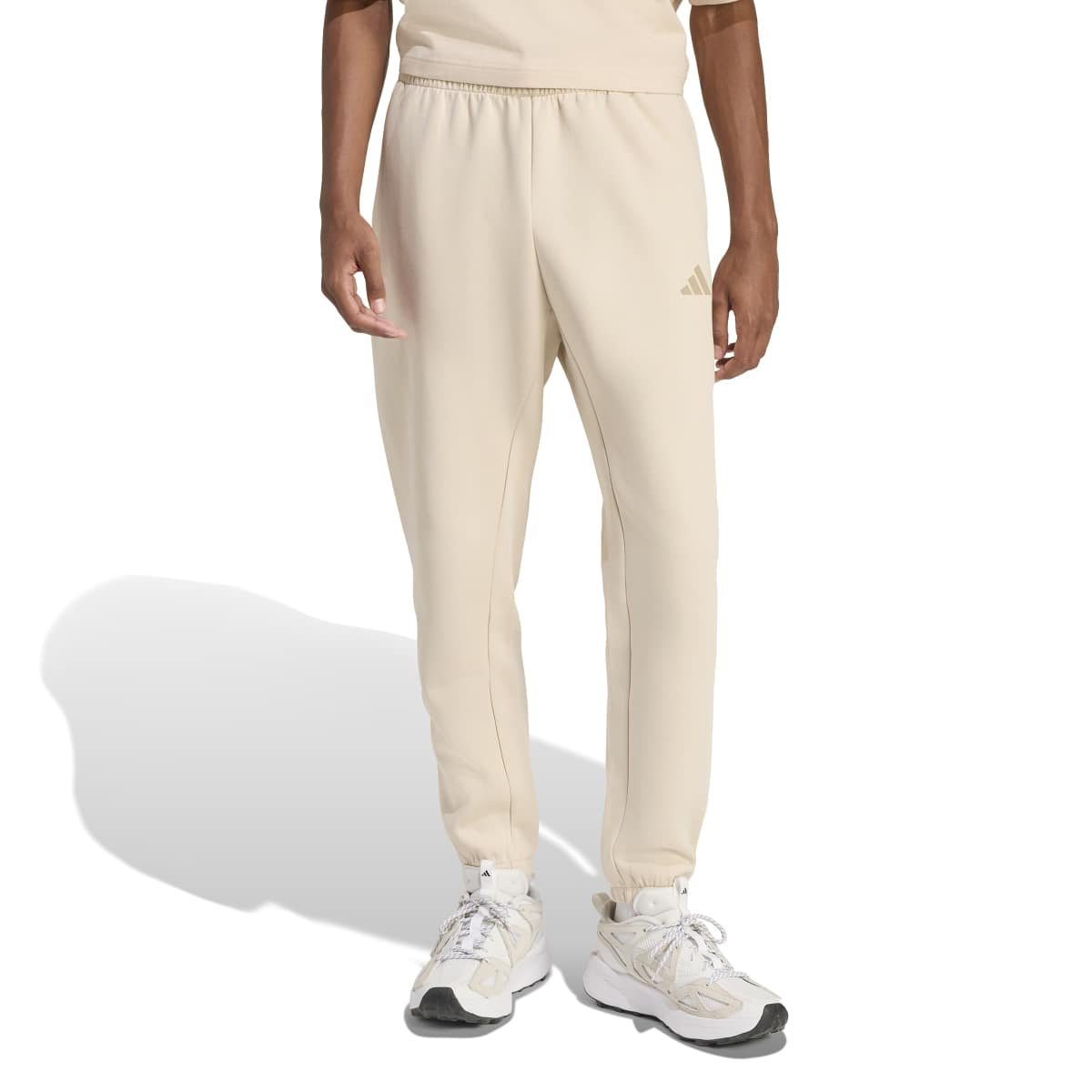 Šviesiai kreminės vyriškos Adidas Future Icons sportinės kelnės su siaurėjančiomis klešnėmis ir mažu logotipu, modelis KD7641.